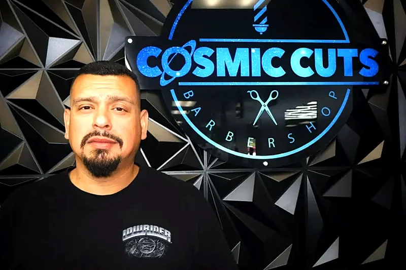 Client in front of the Cosmic Cuts neon logo